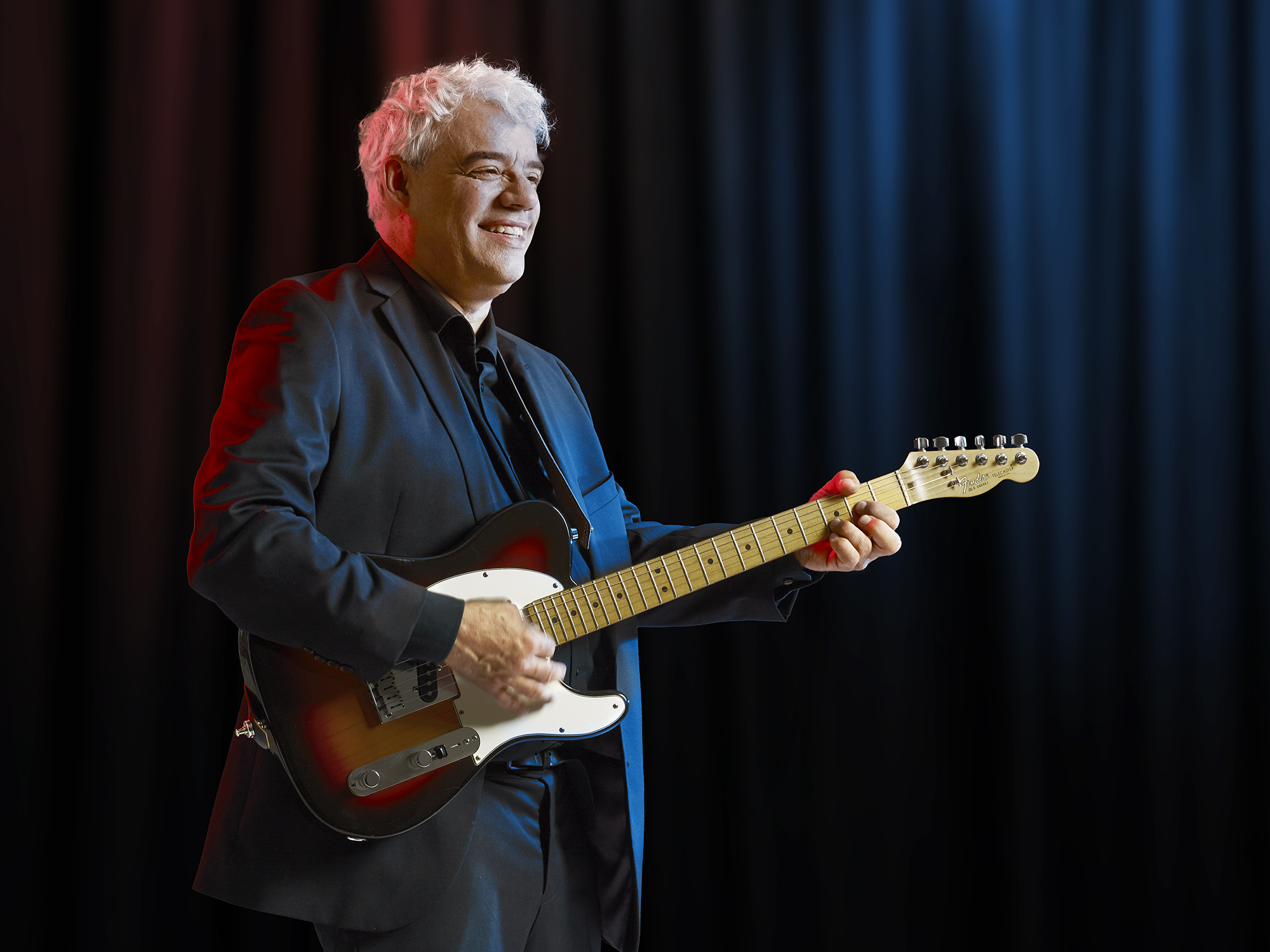 Jean-François Thibaud, chansonnier qui joue de la guitare sur un stage.